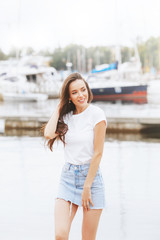 Obraz premium Young beautiful happy woman walks on beach in marina