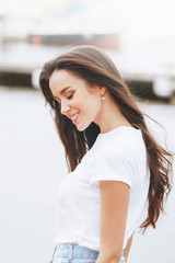 Young beautiful happy woman walks on beach in marina