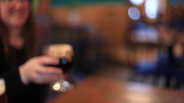 Selective shot of three friends clinking organic red wine and white wine glasses while gossiping and relaxing in brewery pub