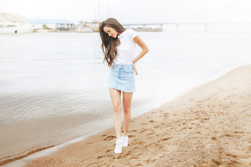 Young beautiful happy woman walks on beach in marina