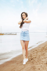 Young beautiful happy woman walks on beach in marina