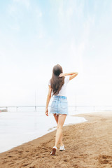Young beautiful happy woman walks on beach in marina