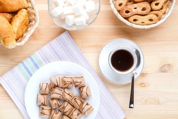 Cup of coffee on a napkin a wooden table and sweets with sugar.