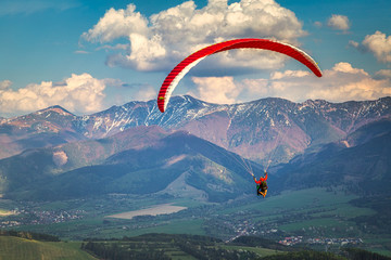 Flying paraglider from the Stranik hill over the mountainous landscape of the Zilina basin in the north of Slovakia..Mala Fatra National Park in the background, Slovakia, Europe.. - obrazy, fototapety, plakaty