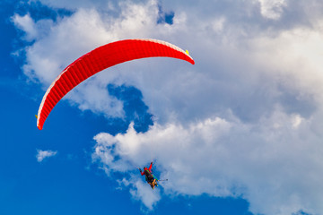 Flying paraglider on a background of blue sky with clouds.