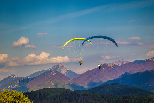 Flying paragliders from the Stranik hill over the mountainous landscape of the Zilina basin in the north of Slovakia..Mala Fatra National Park in the background, Slovakia, Europe.