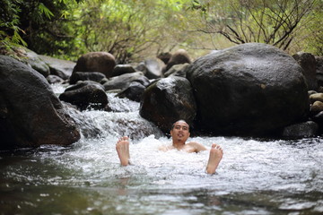 A man is bathing in the Trok Nong waterfall in Chanthaburi, Thailand.