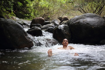 A man is bathing in the Trok Nong waterfall in Chanthaburi, Thailand.