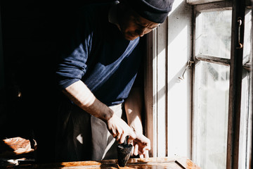 male artisan processes an array of wood with epoxy varnish. renovation of antique furniture.