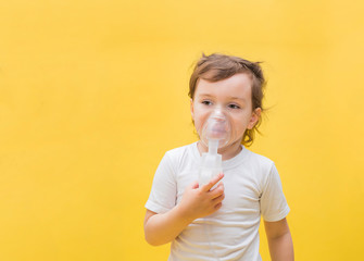 A little girl with an inhaler on a yellow background with copy space. Cute blonde girl with a mask...