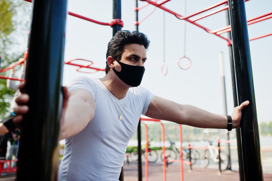 Portrait Sports Arabian Man In Black Medical Face Mask Doing Workout Exercises In Outdoor Gym Place During Coronavirus Quarantine.