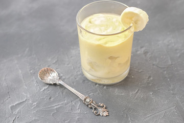 iced frothy banana smoothie. cool summer dessert for hot days. banana puree in a glass with spoon...