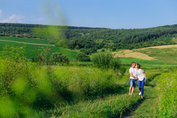 Naklejka na ściany i meble beautiful sunny day. meadow with green grass and forest. couple