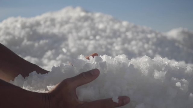 raw salt crystals in hands. Male hand holding natural salt crystals on the background of a salt lake. White natural salt. natural resources concept,