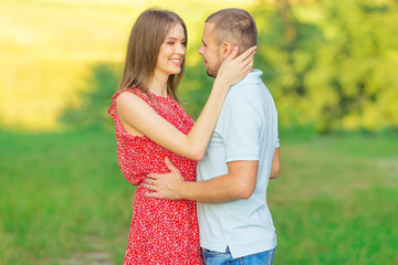 guy and girl embracing each other on the green meadow. close up.