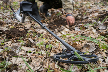 A metal detector in the foreground and looking for ancient old .historical coins or a valuable digger. .Archaeologist search for valuable finds or jewelry in the forest