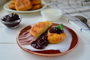 Fat-free cottage cheese pancakes with berry jam and mint. Syrniki with black currant jam and sour cream.