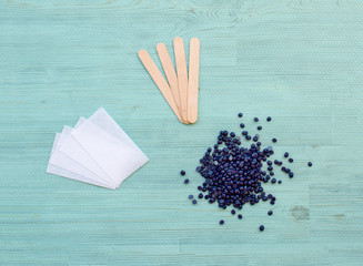 Flat lay beauty cosmetology tools for depilation body. Wax granules lavender with wood spatulas and...