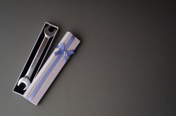 Wrench in gift box on gray background. Greeting card to celebrate Father's day with copy space. Creative surprise for man. 
Successful business concept
