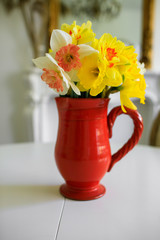 yellow narcissus in vase on white table