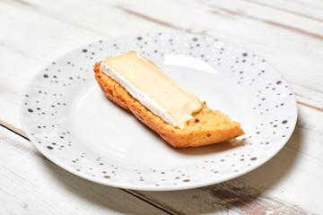 Bread with brie cheese on a plate on a wooden background.