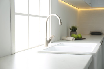 Fototapeta na wymiar New ceramic sink and modern tap in stylish kitchen interior