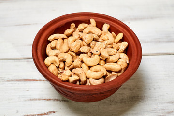 Cashew nuts in a bowl on a wooden background.