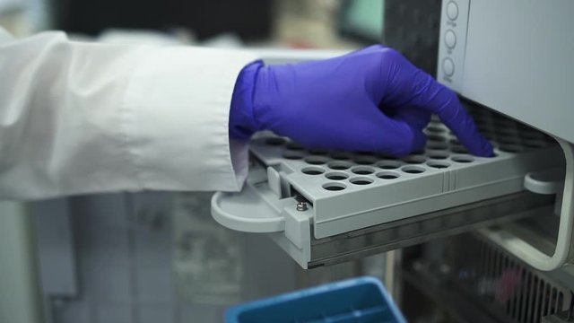 closeup doctor scientist inserting bottles dna hiv blood test tubes in pcr machine Spbd. chemist hand preparing bottles for analyzing in pcr diagnostics machinery. pharmaceutical equipment