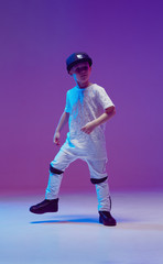 Cool young boy child dancing hip hop in the Studio against the background of neon lights. Break...