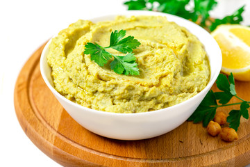 Cooked hummus with avocado in a white bowl on a server table closeup. Tasty and healthy vegetarian food, arab cuisine.