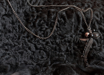 bijouterie. the necklace lies on a black sheep skin. contrast. the stones shimmer from the natural sun color.