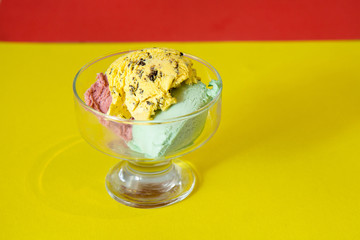 Strawberry, mint and banana ice cream in a cream bowl on a bright yellow background.