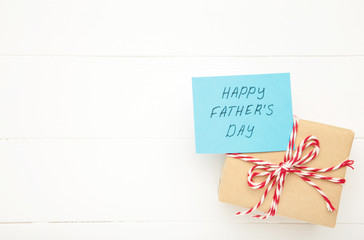 Fathers Day message and gift on white wooden background