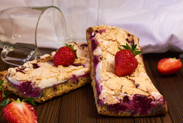 Wooden dark background of planks, white cloth, glasses with tea and homemade pie with cherries and strawberries. Delicious pastries for breakfast.