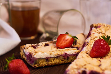 Wooden dark background of planks, white cloth, glasses with tea and homemade pie with cherries and strawberries. Delicious pastries for breakfast.