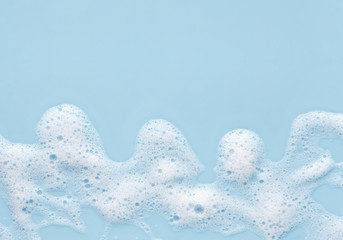 poster with waves of soap foam on blue background, with copy space