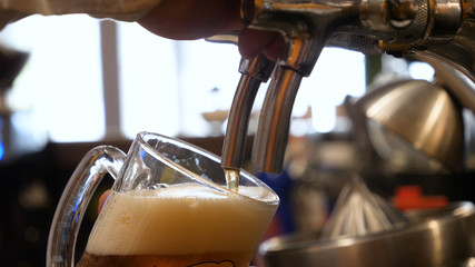 Barman hand at beer tap pouring a draught lager beer serving in a restaurant or pub.