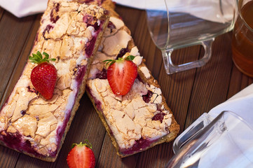 Wooden dark background of planks, white cloth, glasses with tea and homemade pie with cherries and strawberries. Delicious pastries for breakfast.