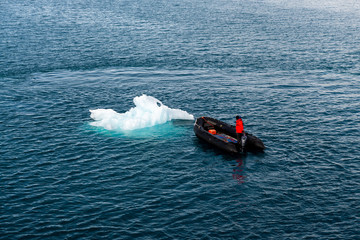Maneuvering orange lifeboat in water in Arctic waters, Svalbard. Abandon ship drill. Lifeboat...