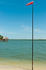 Front view, medium distance of a wind sock on a tall pole, at a tropical marina to measure wind speed and direction to provide information to help sailing ships personal safety for people and sailboat