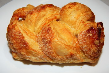 Homemade puffs with sugar on a white plate close-up.