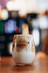 transparent glass with foamy coffee with milk and ice, summer version of Dalgano coffee on the bar...