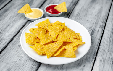 Mexican nachos chips in a white plate on a wood background