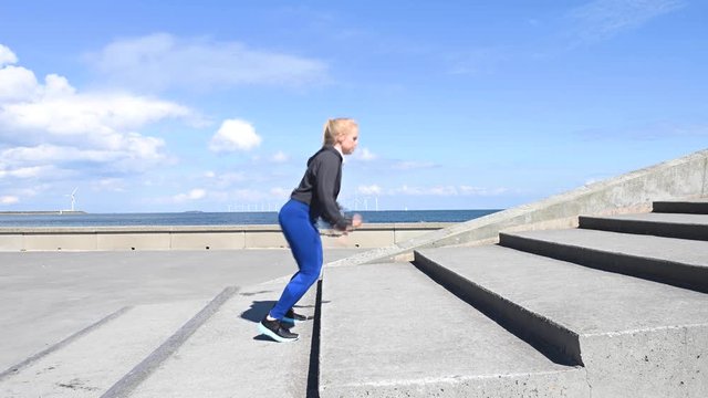Attractive, fit, young woman doing jump exercises on stairs, in slow motion, stock footage by Brian Holm Nielsen