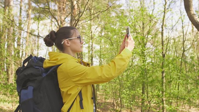Young hiking woman taking photo with smart phone in forest