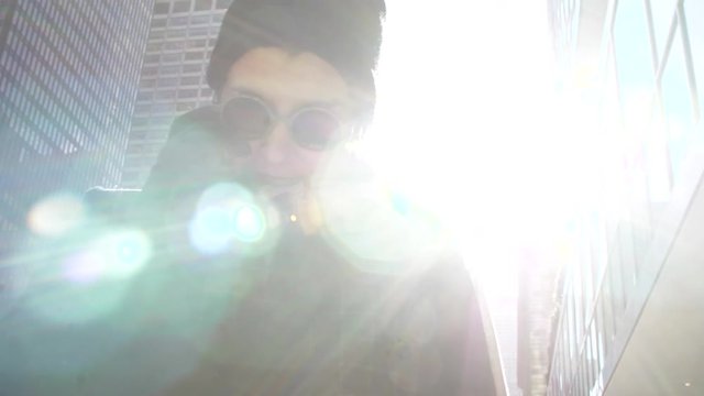 Young woman wearing beanie and glasses ona phonecall in new york city. Skyscrapers on the background.