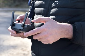 Man holds a drone remote control panel on blurred background, selective focus. Drone control panel in the hands of a man. Drone control.  Aerial surveillance