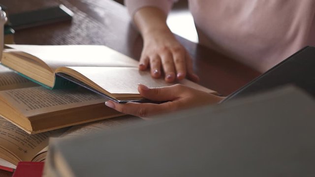 Young Woman Student Reading Text in Paper Book. Girl Pupil is Reading a Book Sitting Home at the Table. Woman Studying. Home Learning. Distance Education. Smart Clever Woman. Knowledge Literature.