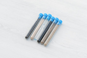 Samples of different types of soil in test tube on the table. Soil science concept.