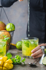 Fresh mango mojito cocktail with lime and mint in a glass